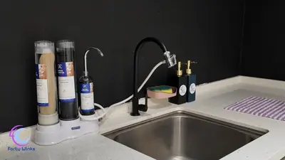 a kitchen sink with a faucet and several bottles ofmetics at The Horizon Ipoh by 40 Winks in Ipoh