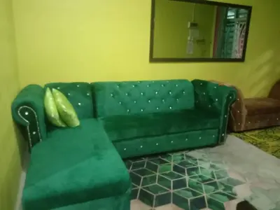 a green couch in a living room with a mirror at Sinakhan Homestay in Gua Musang