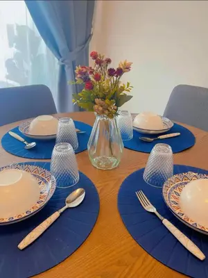 a table with plates and utensils and a vase of flowers at Hidden Plan Homestay in Kepala Batas