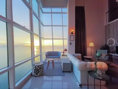 a living room with a couch and a large window at Fascinating Seaview Apartment at Maritime Penang in Jelutong