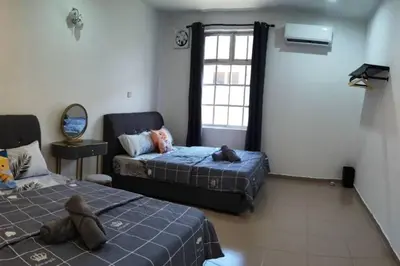 a teddy bear sitting on a bed in a room at Cozy Deluxe House Padang Serai 28pax in Padang Serai