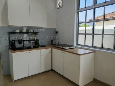 a kitchen with white cabinets and a window at Cozy Deluxe House Padang Serai 28pax in Padang Serai