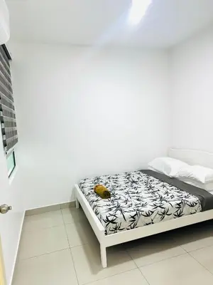 a bed in a white room with a yellow object on it at Spc Arena Apartment Service in Bayan Lepas