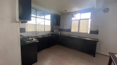 a kitchen with black cabinets and a sink and two windows at Srinibong hotel apartment in Nibung Tebal