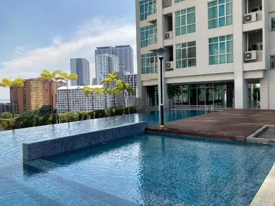 a swimming pool in front of a building with a city at 1BR Condo Straits Garden Suites Georgetown Penang in George Town