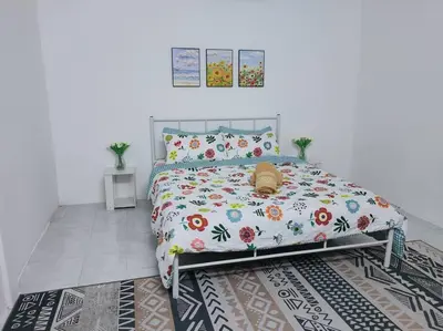 a bedroom with a bed with a floral bedspread at CASA AIRA Cozy & Comfy Home in Kampong Kepayang