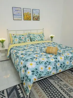a bed with a blue and white comforter with yellow and white flowers at CASA AIRA Cozy & Comfy Home in Kampong Kepayang