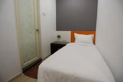 a bedroom with a large white bed and a window at Big Orange Hotel Sungai Petani in Sungai Petani
