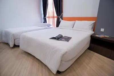 a hotel room with a bed with a book on it at Big Orange Hotel Sungai Petani in Sungai Petani