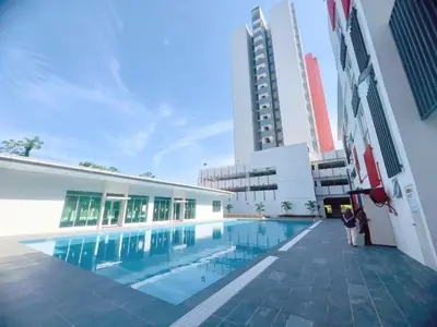 a woman standing next to a building with a swimming pool at The Floral Dawn Anderson in Kampong Simee