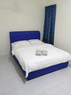a blue bed with two slippers on top of it at The Welcome Mat Homestay in Seri Iskandar