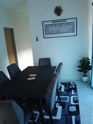 a dining room with a black table and chairs at The Welcome Mat Homestay in Seri Iskandar