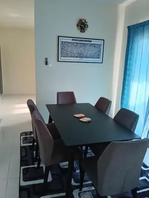 a black dining room table and chairs in a room at The Welcome Mat Homestay in Seri Iskandar