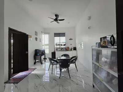 a living room with a table and a ceiling fan at The Bangau Cottage in Sungai Petani