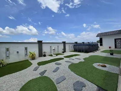 a patio with grass and rocks and a building at The Bangau Cottage in Sungai Petani