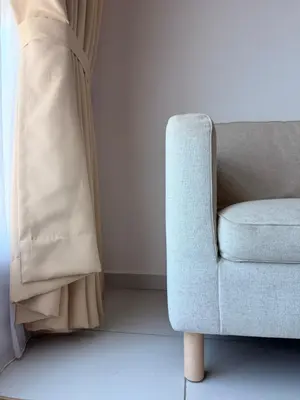 a blue chair in a living room next to a curtain at NeoSkyhigh Suites in Batu Kawan