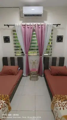 a room with two beds and a window with pink curtains at Zulfa Homestay Teluk Intan in Teluk Intan
