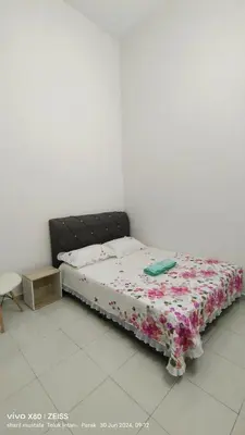 a bedroom with a bed with a floral bedspread at Zulfa Homestay Teluk Intan in Teluk Intan