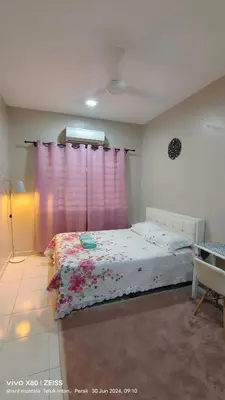 a bedroom with a bed with a pink curtain at Zulfa Homestay Teluk Intan in Teluk Intan