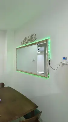 a mirror on a white wall with a wooden table at Zulfa Homestay Teluk Intan in Teluk Intan