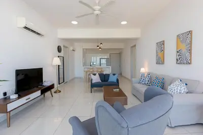 a living room with two blue chairs and a tv at Jazz Luxury Suites BY MEXI in Tanjong Tokong