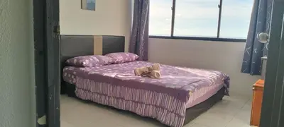 a bedroom with a bed with purple sheets and a window at Bayu Emas Apartment in Batu Ferringhi