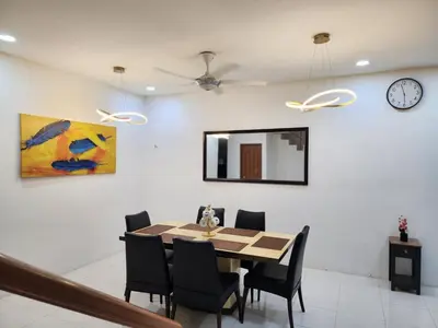 a dining room with a table and chairs and a clock at Dirgahayu Homestay I Rajawali in Kulim