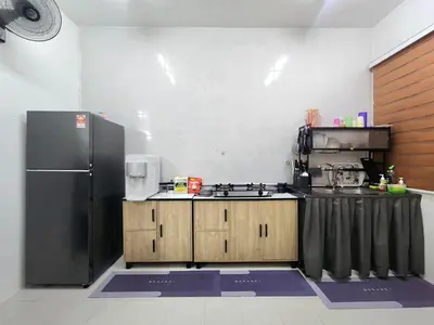 a kitchen with a black refrigerator and wooden cabinets at Dirgahayu Homestay I Rajawali in Kulim