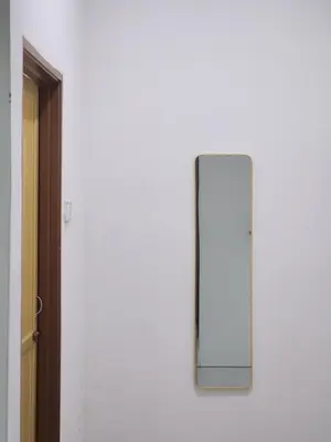 a mirror on a white wall next to a door at Dirgahayu Homestay I Rajawali in Kulim