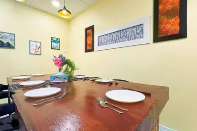 a wooden table with white plates and utensils on it at Bercham 81 Homestay in Ipoh