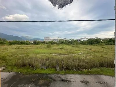 a field of grass with a building in the background at BYSS Homestay Studio in Kampar