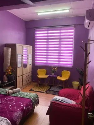 a purple bedroom with two beds and a table and chairs at Brite Homestay Nibong Tebal in Kampong Telok