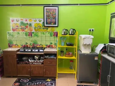 a kitchen with a yellow shelf and a green wall at Brite Homestay Nibong Tebal in Kampong Telok
