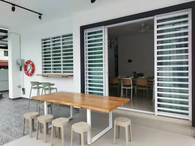 a dining room with a wooden table and stools at Tints of Green Pool Bungalow-6 Bedroom-Karaoke-BBQ in Sultan Azlan Shah Airport