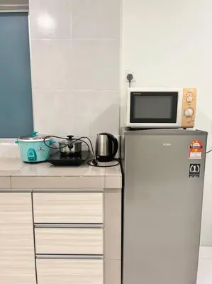 a microwave on top of a refrigerator in a kitchen at Lily Brava 5 in Tanah Rata