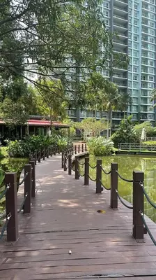 a wooden walkway in a park with buildings in the background at Ipoh lakeside Suite Ipoh 4pax in Ipoh