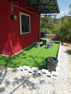 a yard with green grass and a red building at Bougainvillea Garden KKB in Kuala Kubu Baharu