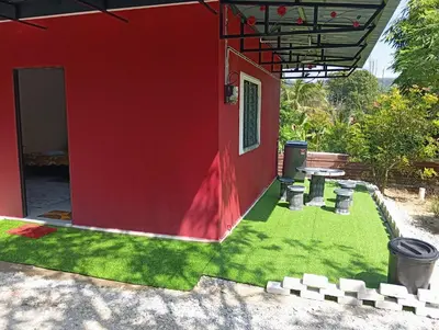 a red house with a yard with green grass at Bougainvillea Garden KKB in Kuala Kubu Baharu