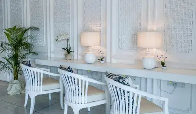 a dining room with white chairs and a table with two lamps at Hotel 19, Penang in George Town