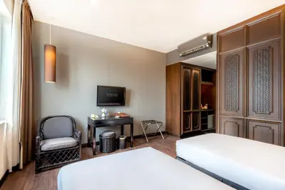 a bedroom with two beds and a tv and a chair at Hotel 19, Penang in George Town