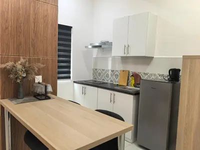 a kitchen with white cabinets and a wooden table at Ipoh Anderson Suite 1802 By Hopestay in Ipoh