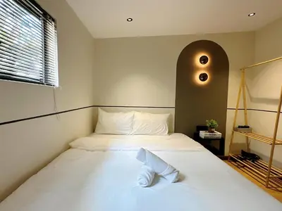 a bedroom with a white bed with a large window at The Jubilee Guest House in Ipoh