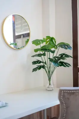 a vase with a plant on a table with a mirror at The Bibik at 8 Clarke -NEW Entire #Unesco #HeritageHome in George Town