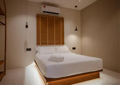 a bedroom with a white bed with a fan on the wall at Ipoh Tiga Pool Villa by Papahost in Ipoh