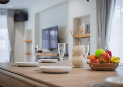 a wooden table with glasses and a bowl of fruit at Ipoh Tiga Pool Villa by Papahost in Ipoh