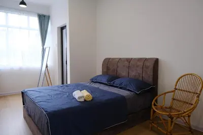 a bedroom with a bed with a blue bedspread and a chair at Homestay Bukit Mertajam - DHome in Bukit Mertajam
