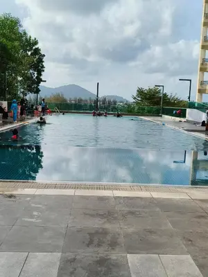 a large swimming pool with people sitting around it at Marina Heights Apartment in Lumut