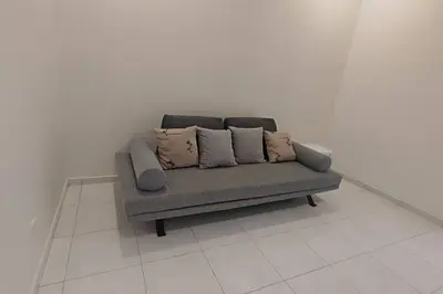 a couch with three pillows sitting on a white floor at Super Minimalist SP Town Centre in Sungai Petani