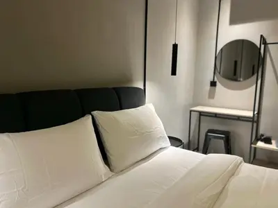 a bedroom with a bed with white sheets and a mirror at M2 Living Townhouse in Ipoh in Ipoh