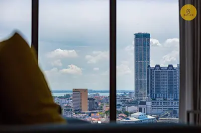 a person looking out of a window at a city at Seaview 2BR Infinity Pool & EasyAccess to Town 13A in George Town